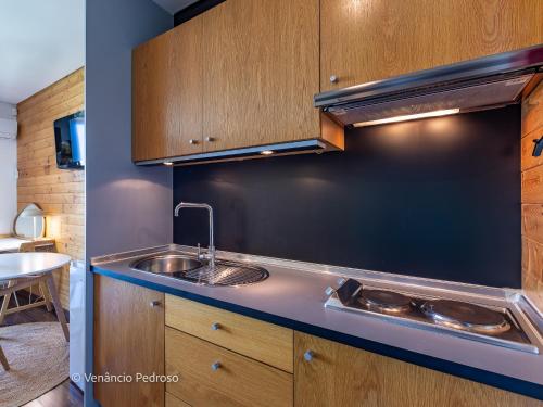 a kitchen with a sink and wooden cabinets at Ericeira Coxos Beach Lodge in Santo Isidoro