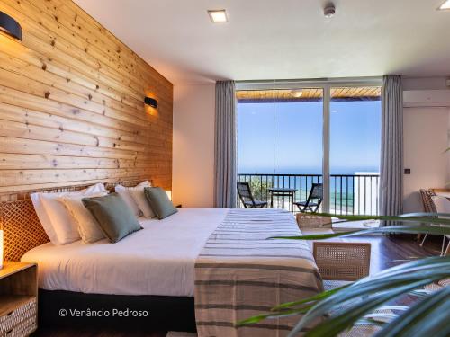 a bedroom with a large bed with a wooden wall at Ericeira Coxos Beach Lodge in Santo Isidoro
