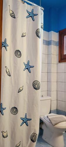 a bathroom with a shower curtain with fish and shells at Tsonos Apartments in Keramídhion