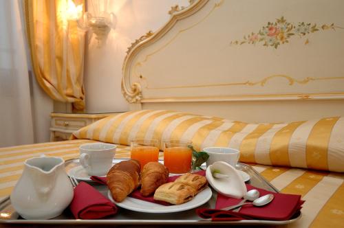 un vassoio di prodotti da forno e succo d'arancia su un letto di Casa Sul Molo a Venezia