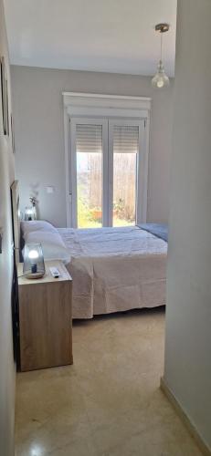a bedroom with a large bed and a window at Apartamento con jardin in La Línea de la Concepción