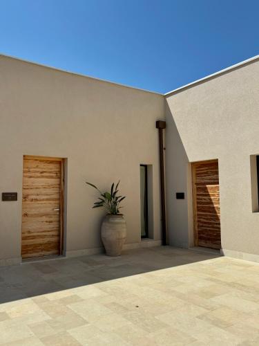 a building with two doors and a plant in a pot at Chiusa Di Carlo Agriturismo in Avola