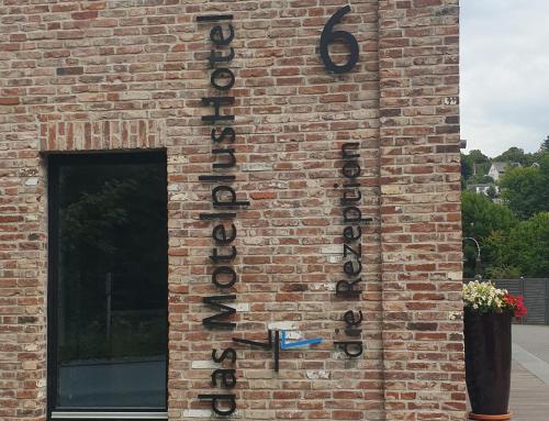 a brick wall with a sign on it at MotelplusHotel BiggeSeeFront in Olpe