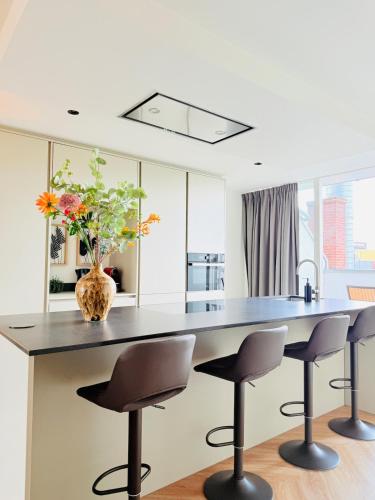 a kitchen with a large table with two chairs and a vase with flowers at Cooth's Luxury Loft with City Views in Breda
