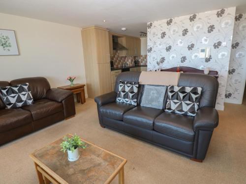 a living room with two leather couches and a table at Pears Suite in Whitehaven
