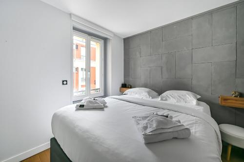 ein Schlafzimmer mit einem großen weißen Bett mit Handtüchern darauf in der Unterkunft Le Sorrento - 2 prs - Métro 12 - Proche Paris in Vanves