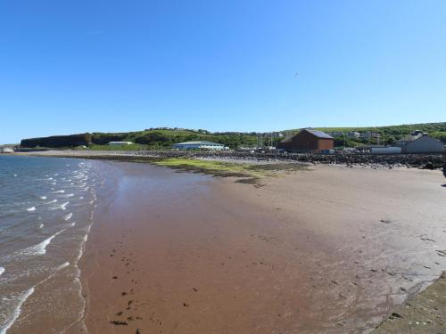 a sandy beach with a group of buildings in the background at Pears Suite in Whitehaven