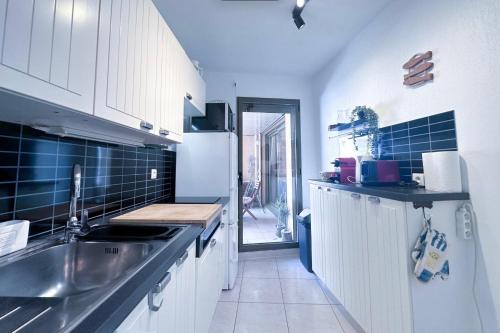 La cuisine est équipée de placards blancs, d'un évier et d'un comptoir. dans l'établissement Charming T2 near the Port Vauban d'Antibes, à Antibes