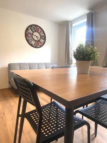 a dining room table with two chairs and a clock on the wall at Bergluft TOP 3 Modern Apartment with 2 bedrooms 1 hour from Vienna - Parking & 24 hour Self Check-in in Grafenbach