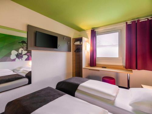 a hotel room with two beds and a tv at B&B Hotel Bochum-Herne in Herne