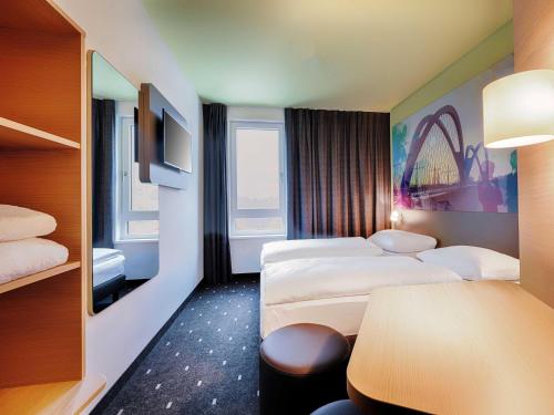 a hotel room with two beds and a table at B&B Hotel Kehl in Kehl am Rhein