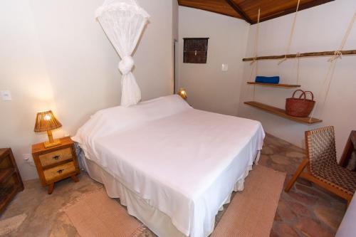 a bedroom with a white bed and a chair at Pousada Capitù in Imbassai