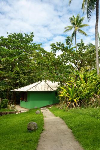 a green building next to a dirt road at Pousada Capitù in Imbassai