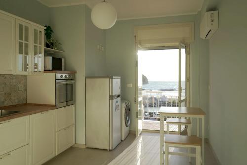 a kitchen with a refrigerator and a table with a view of the ocean at La voce del mare in Agropoli