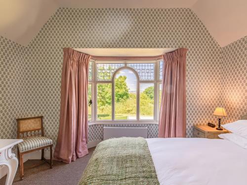 ein Schlafzimmer mit einem Bett und einem großen Fenster in der Unterkunft Dairy Cottage in Aylesbury