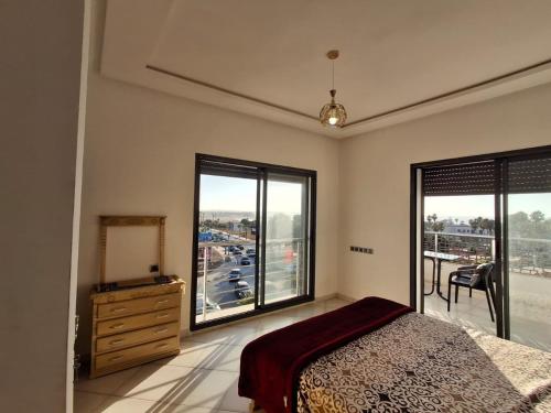 a bedroom with a bed and a dresser and windows at البحر والشمس والطبيعه in Pont Blondin