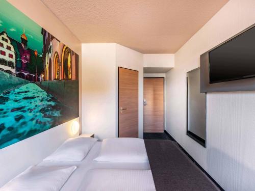 a room with a bed and a flat screen tv at B&B Hotel Freiburg-Nord in Freiburg im Breisgau