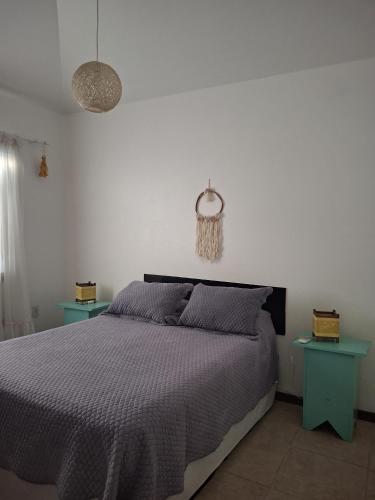 a bedroom with a bed and two blue tables at Condominio Vila Lila in Garopaba