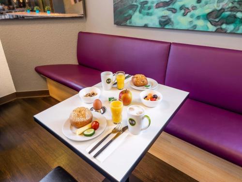 a table with plates of food on a purple couch at B&B Hotel Freiburg-Nord in Freiburg im Breisgau