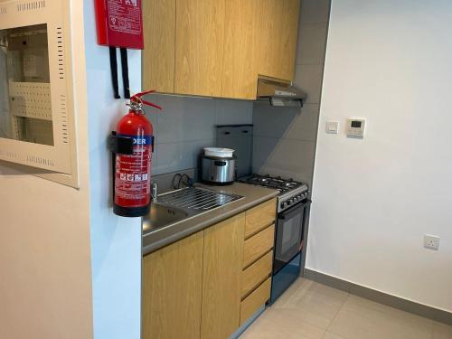 een keuken met een brandblusser aan de muur bij lenexusholidayhomes in Sharjah