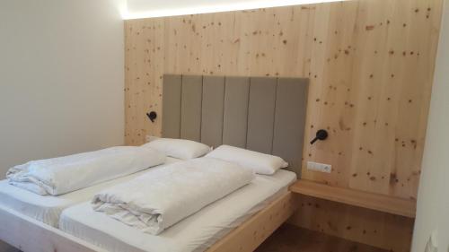 a bed with white sheets and pillows in a room at Mitterhofer Appartements in Villandro