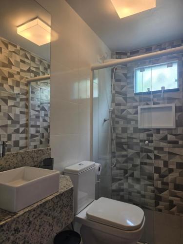 a bathroom with a white toilet and a sink at Vila Alegria in Bombinhas