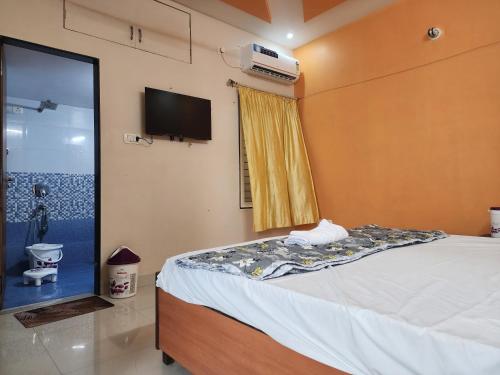 a bedroom with a bed and a tv on the wall at dwarika home stay ujjain in Ujjain