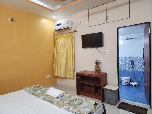 a room with a bed and a tv on the wall at dwarika home stay ujjain in Ujjain