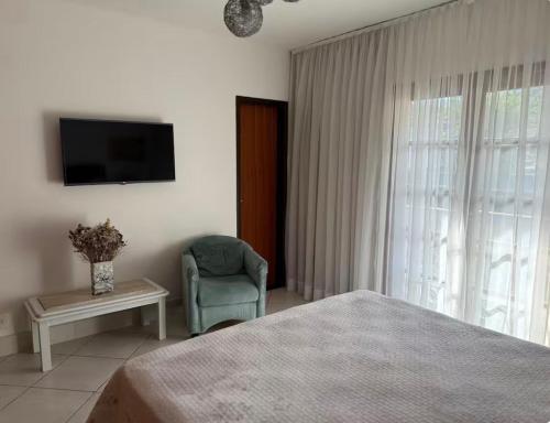 a bedroom with a bed and a chair and a television at Casa Klippel in Petrópolis