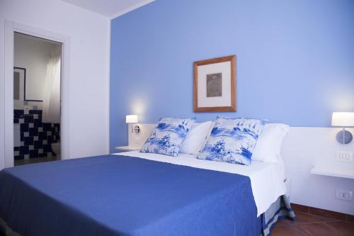 a blue bedroom with a bed with blue sheets and pillows at B&B L'Artista in Portopalo