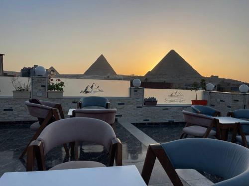 a patio with chairs and tables and pyramids in the background at Pyramids Khufu Solar Boat Hotel in Cairo