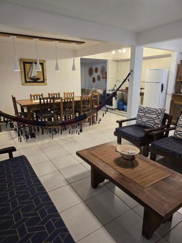 a room with tables and chairs and a hammock at Vila Alegria in Bombinhas