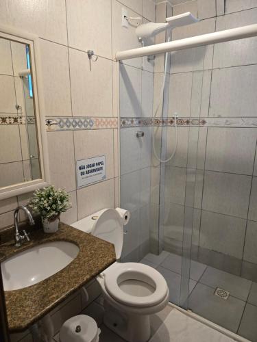 a bathroom with a shower and a toilet and a sink at Vila Alegria in Bombinhas