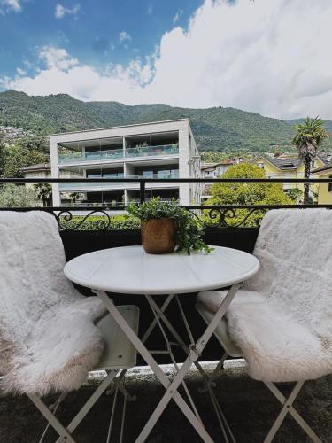 a white table and chairs on a balcony with a building at Angoli di pace - Appartamento trilocale in Muralto