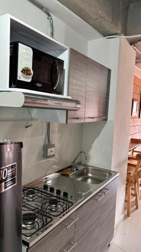eine Küche mit einer Mikrowelle über einem Herd und einer Spüle in der Unterkunft Envigado Apartaestudio in Envigado