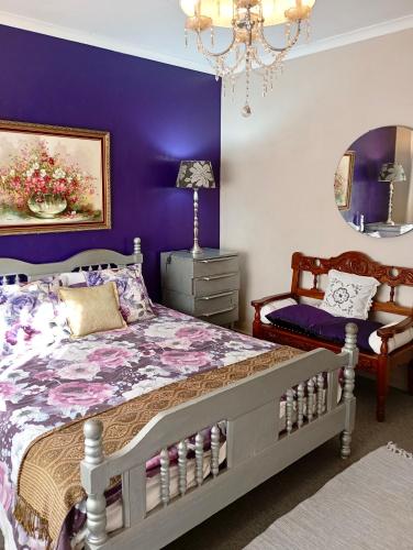 a purple bedroom with a bed and a chair at The Secret Garden Mossel Bay in Mossel Bay