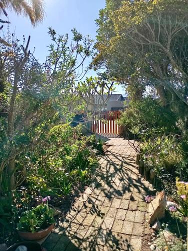 a garden with a brick walkway with plants and trees at The Secret Garden Mossel Bay in Mossel Bay