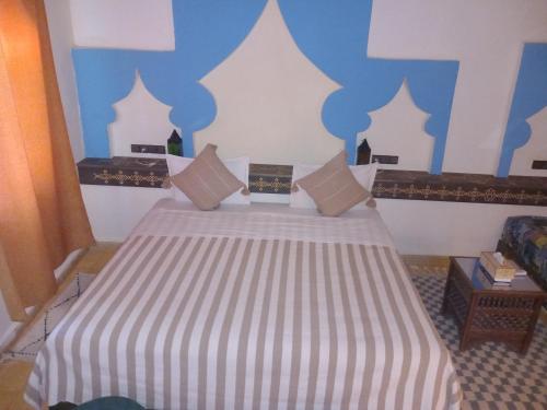 a bedroom with a bed with a blue and white wall at Maison Mirage B&B in Hassilabied