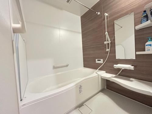 une salle de bain avec une baignoire blanche et une douche dans l'établissement Jun resort 梅, à Kujukuri