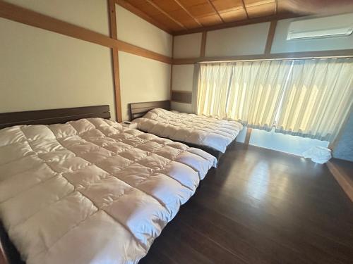 deux lits dans une chambre avec une grande fenêtre dans l'établissement Jun resort 梅, à Kujukuri