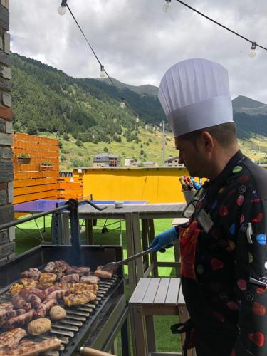 a man is cooking food on a grill at Wuau! Hotel Galanthus & Spa in Soldeu