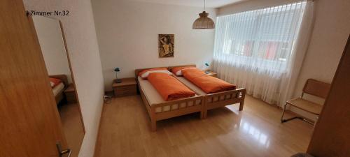 a bed with orange pillows in a room with a window at Apartments Haus Quelle in Leukerbad