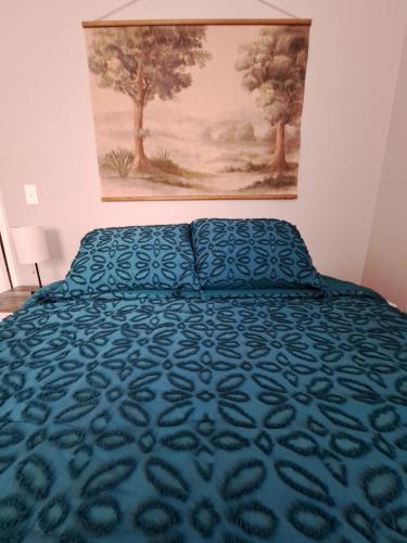 a bed with a blue bedspread and a painting on the wall at Illini Hideaway in Streator