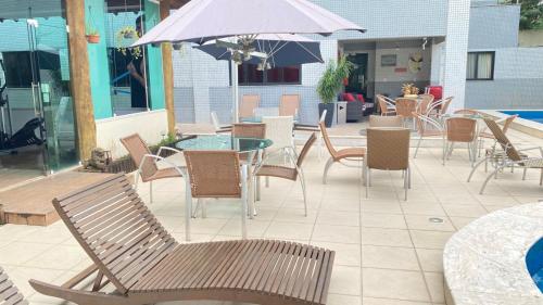 a patio with chairs and tables and an umbrella at Camaçari Plaza Hotel in Camaçari