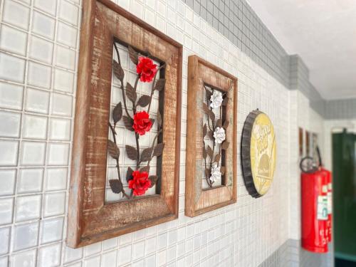 two picture frames with red flowers on a wall at Camaçari Plaza Hotel in Camaçari