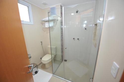 a bathroom with a toilet and a glass shower at Herval Park Hotel in Ponta Porã