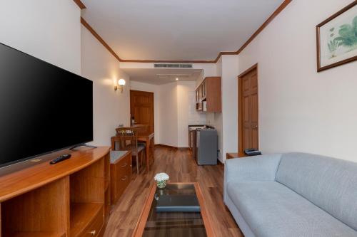 a living room with a couch and a flat screen tv at Grand Diamond Suites Hotel in Bangkok