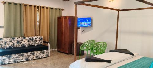 a bedroom with a bed and chairs and a tv at De Orchid Resort in Agonda