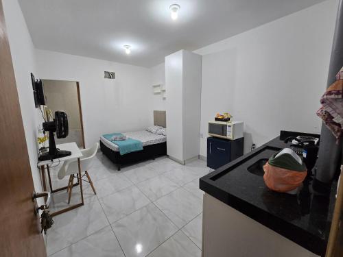 a room with a kitchen and a room with a bed at Flat completo a 5 minutos apé de mercado, farmácia in Aparecida de Goiania
