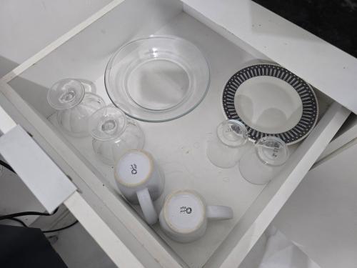 a white table with glasses and a plate and a plate at Flat completo a 5 minutos apé de mercado, farmácia in Aparecida de Goiania